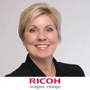 Executive search recruit Vice President Services Sales at Ricoh USA, Cindy Jordan-Ford’s professional headshot. Woman is smiling with ear-length straight hair wearing a button up collared shirt. Ricoh logo pictured underneath woman's headshot